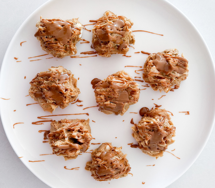 Top-down view of eight Biscoff Oreo Protein Balls with Flow Fuel, artfully arranged on a white platter and drizzled with smooth Biscoff spread.