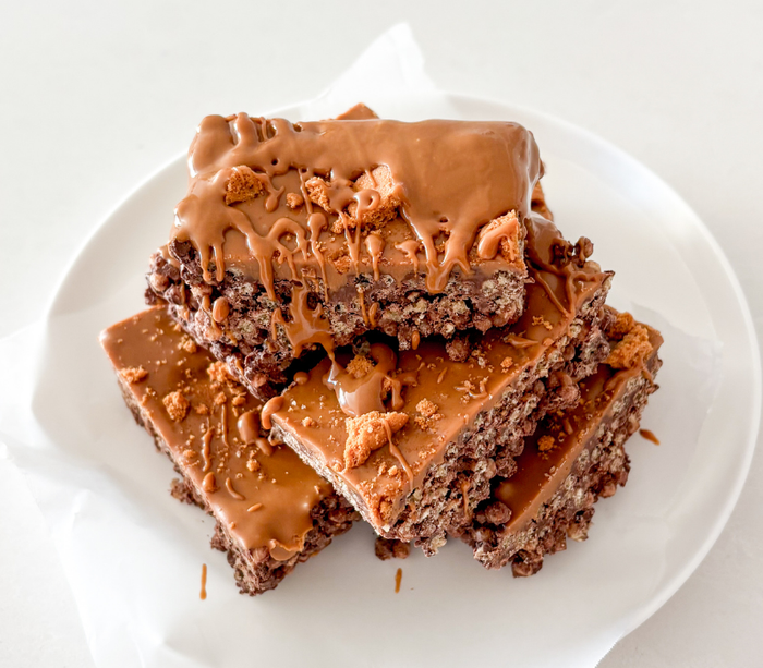 A stacked serving of Biscoff Protein Slice with Voomie Flow Fuel, drizzled with extra Biscoff and sprinkled with crunchy biscuit pieces.